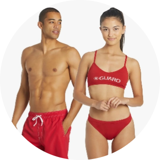 Male and female models wearing lifeguard swimwear. The male model is in red swim trunks, and the female model is in a red bikini with "GUARD" printed on the top.